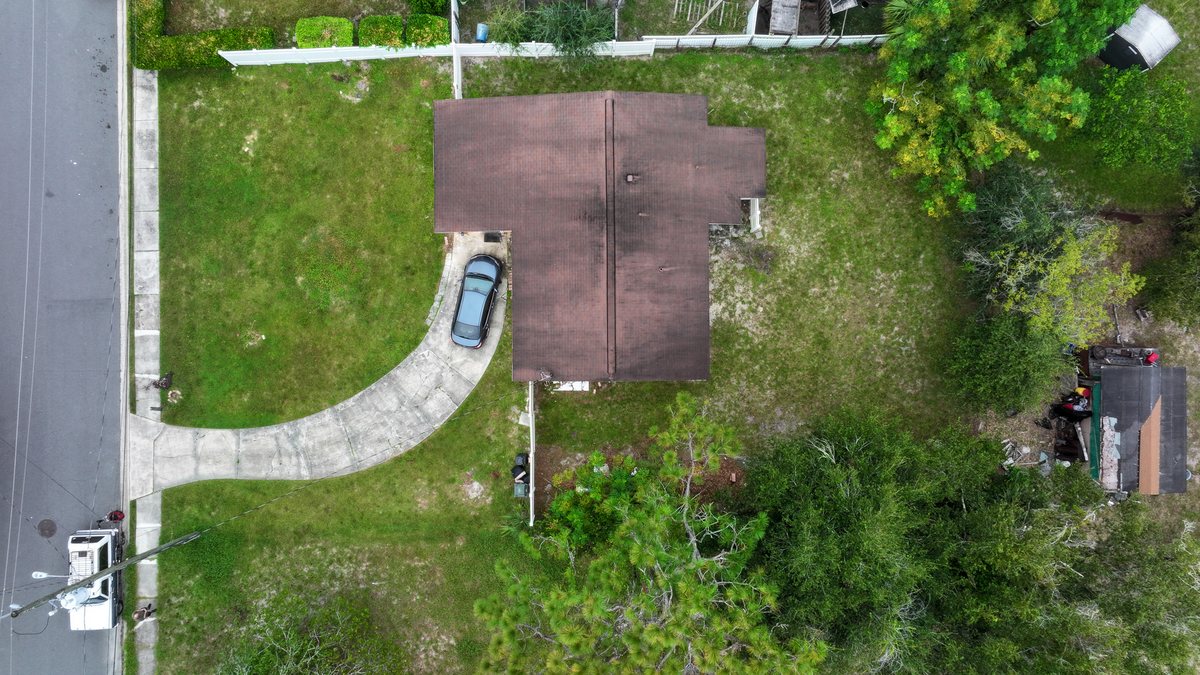 Top-down drone aerial of a Jacksonville home, its roof, curved driveway, street, and full lot