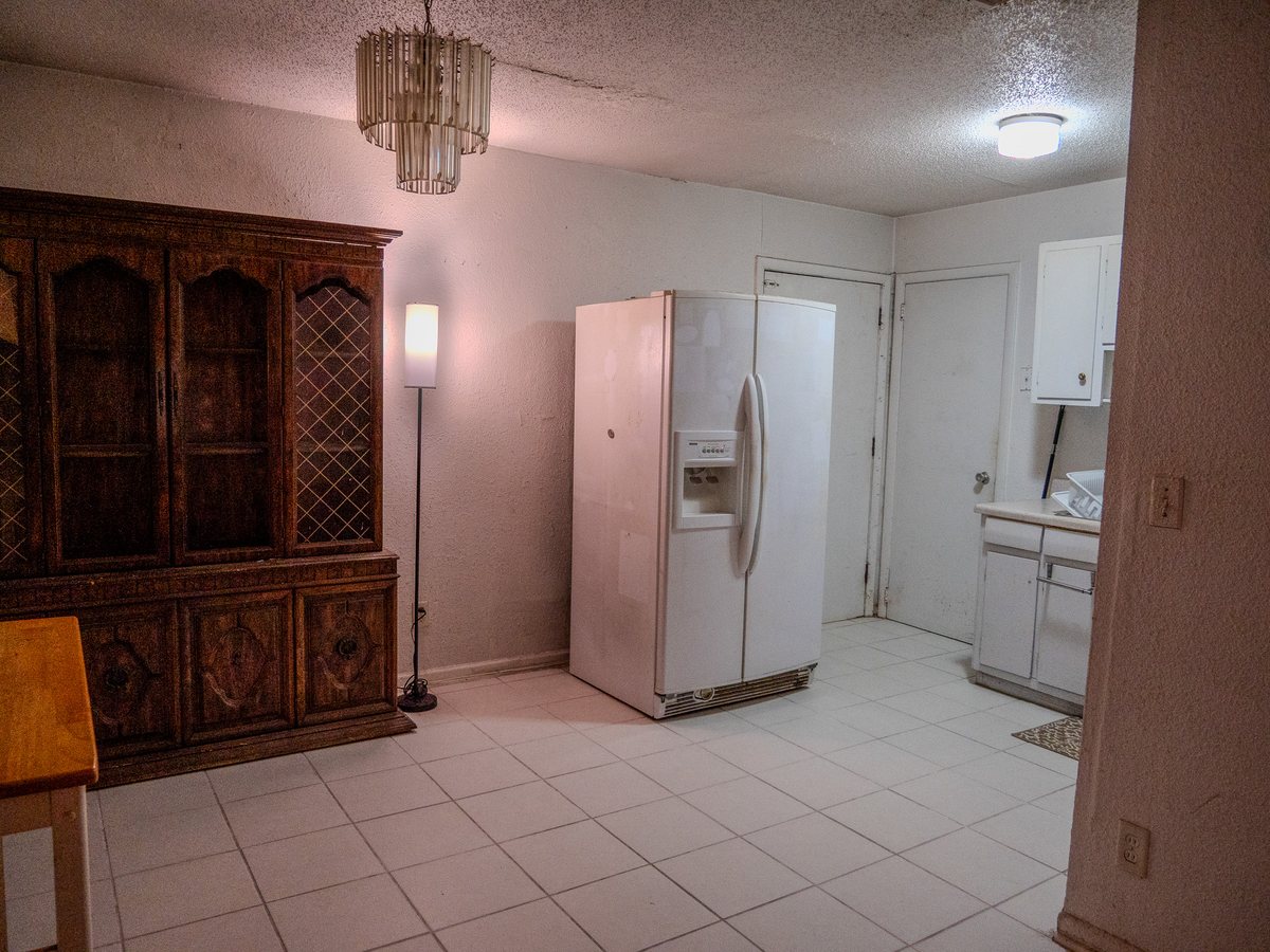 Dining room with a wood hutch and tile floor opening into the kitchen of a Jacksonville home