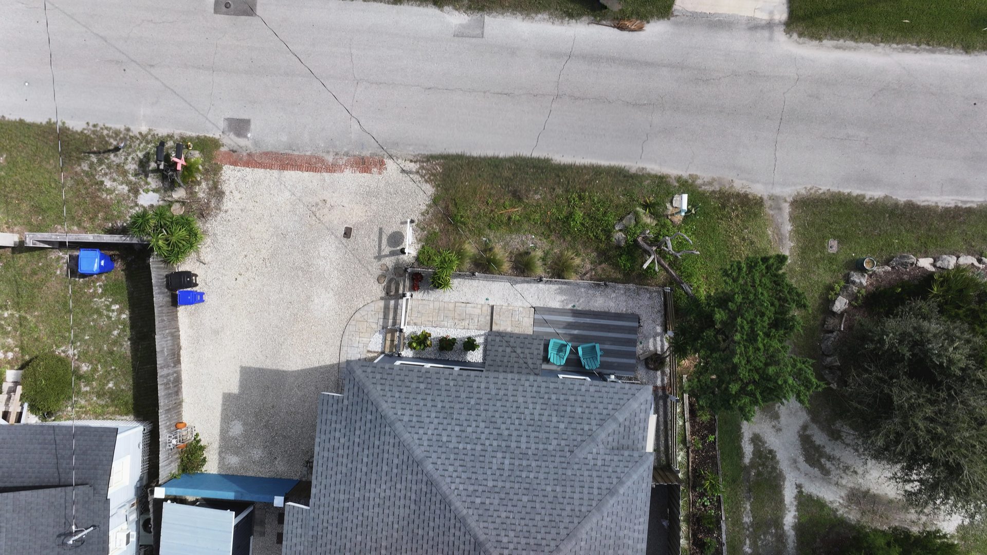 Cleaned top-down drone aerial of a coastal home, its roof, front deck, and street