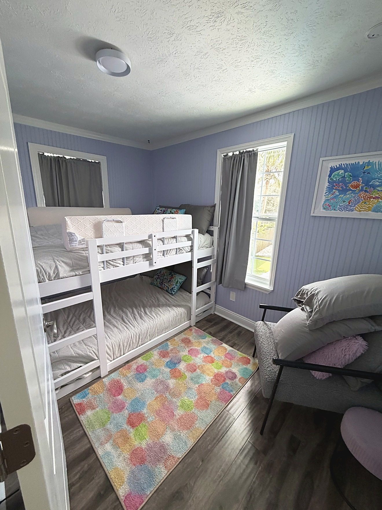 Bunk room with white bunk beds and a colorful rug in a coastal rental home